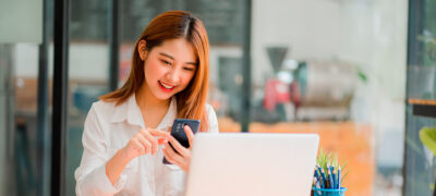 Image: A young woman using a laptop and a smartphone