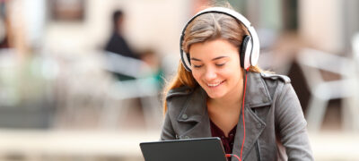 Image: A young woman with headphones using a tablet