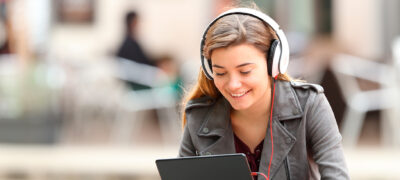 Image: A young woman with headphones and a tablet