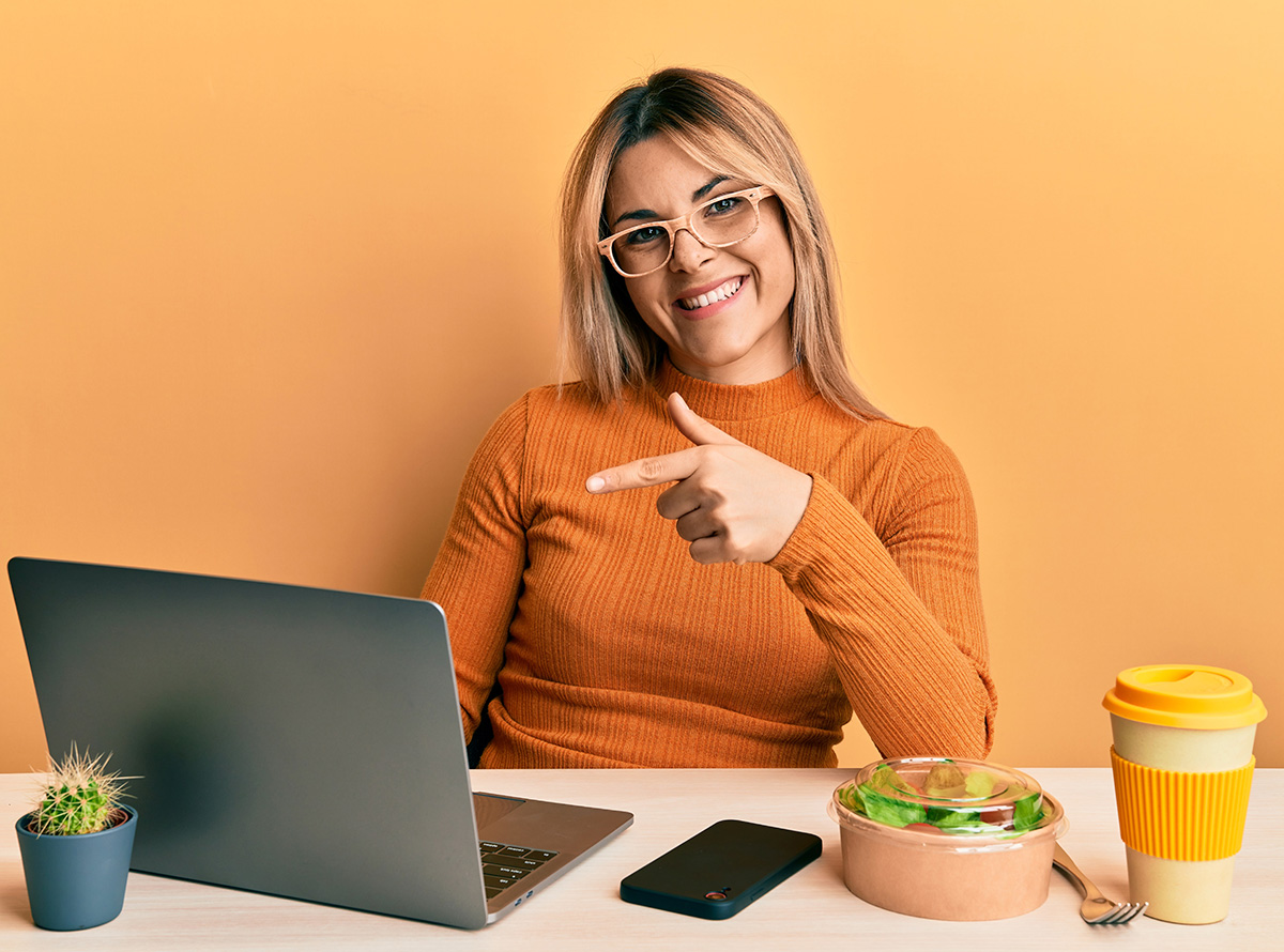 Young female student working at the laptop wearing glasses smiling happy pointing with hand and finger