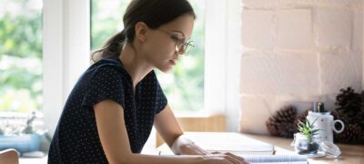 Serious student girl in glasses reading book