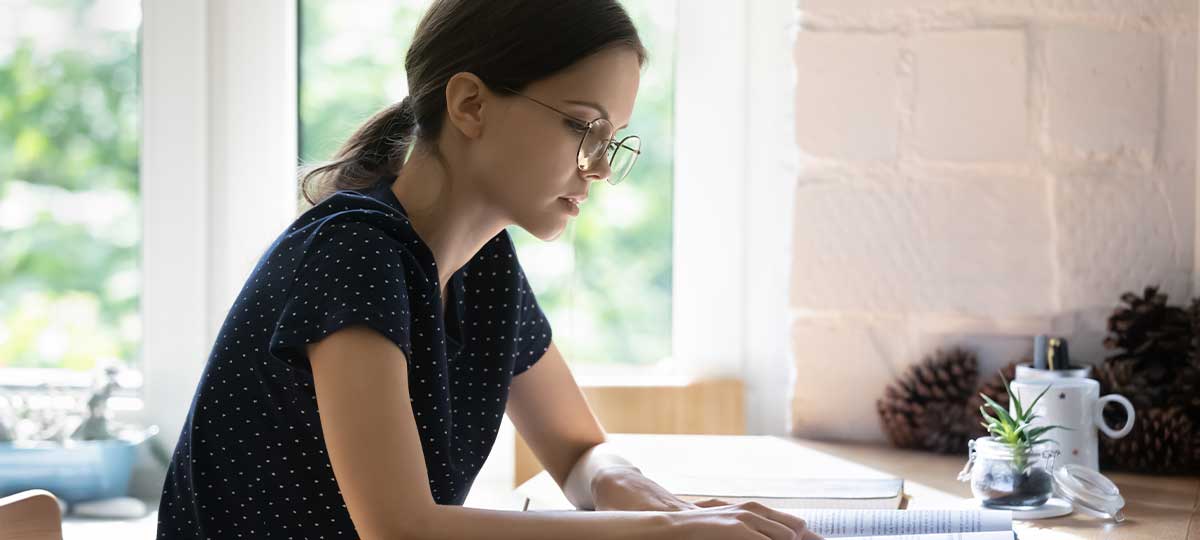 Serious student girl in glasses reading book