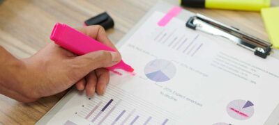 Male hand highlighting important figures in report with bright pink color