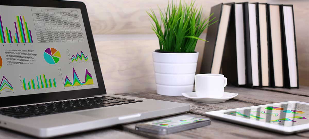 PC, laptop, tablet and phone financial statistics displayed on the screen on wooden table